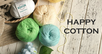 Estako Happy Cotton balls in white, cream, green and teal on whitewashed wood, a soft OEKO-TEX certified cotton blend for baby blankets.