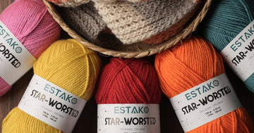 A basket of smooth, colourful Estako Star-Worsted skeins, an easy-to-handle worsted wool blend for beginner knitters and crocheters.