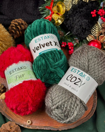 Estako Velvet XL in forest green, Fur in red and Cozy in grey arranged on a wood slice with pinecones, gold bells and holly
