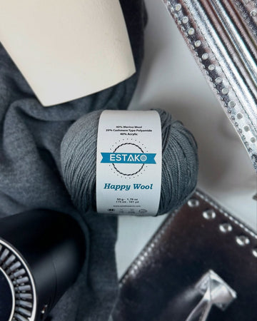 A ball of Estako Happy Wool in grey, a fingering weight merino blend, with the fibre content visible on its band.