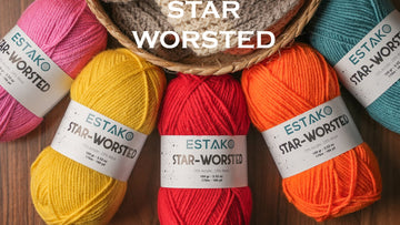 Five Estako Star-Worsted skeins with their care labels visible, arranged around a knitted piece